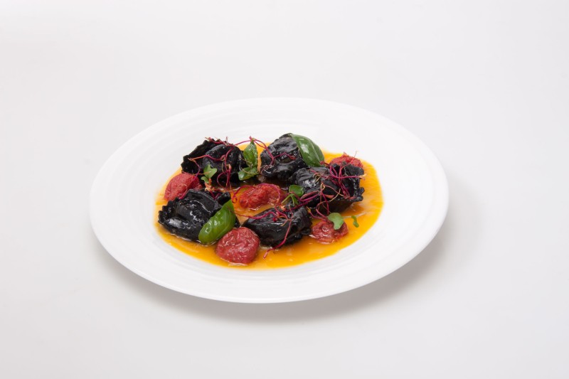 Ravioli di branzino al nero di seppia su passata di datterini gialli e perle di pomodori