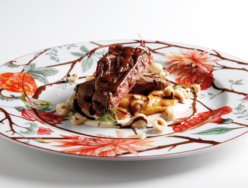 Pluma iberica con porcini trifolati su crema di topinambur, salsa al cioccolato fondente e nocciole tostate